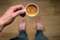 Young man drinking morning coffee and holding mobile phone. Coffee break. Man holding cup of fresh roasted coffee and looking at t Royalty Free Stock Photo