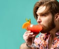 Young man drinking red orange margarita cocktail drink juice happy looking at camera over blue mint Royalty Free Stock Photo