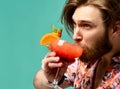 Young man drinking red orange margarita cocktail drink juice happy looking at camera over blue mint Royalty Free Stock Photo