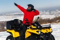 Young man driver dabbing on the ATV quad bike stand in heavy snow with deep wheel track. Moto winter sports.