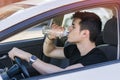 Young man driving car and drinking water from Royalty Free Stock Photo