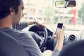 Young man driving car and using mobile phone Royalty Free Stock Photo