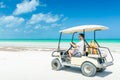 Young man driving golf cart along tropical white sandy beach Royalty Free Stock Photo