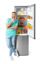 Young man eating apple near open refrigerator