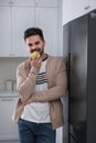 Man eating apple near refrigerator in kitchen Royalty Free Stock Photo