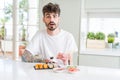 Young man eating asian sushi from home delivery scared in shock with a surprise face, afraid and excited with fear expression Royalty Free Stock Photo