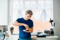 Young man eating carrot stick with hummus dip on the kitchen. Hummus served with raw vegetables on the plate. Healthy food lunch. Royalty Free Stock Photo