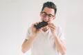 Young man eating a chocolate bar. Nerd is wearing glasses. Royalty Free Stock Photo