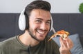 Young man eating delivery pizza at home - Happy guy having meal while video calling with family in living room Royalty Free Stock Photo