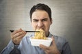 man eating instant noodles while working with in office. Lunch at the office. tasteless junk food Royalty Free Stock Photo