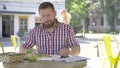 Young man eating lunch and reading newspaper, slider and pan shot righ