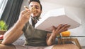 Young man eating pizza delivery at home - Happy guy having meal while playing video games in living room Royalty Free Stock Photo