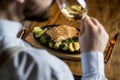 Young man eating salmon fillet with gratinated potatoes, leek and spinach Royalty Free Stock Photo