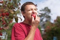 Young man eating a small red apple