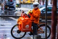 Young man on an electric bike with takeaway.com logo delivering food during a rainy day in Bucharest, Romania, 2020