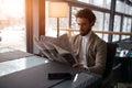 Young man in elegant clothes sitting at a cafe table reading a newspaper Royalty Free Stock Photo