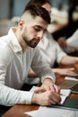 Young man, employee in formal clothes sitting at business meeting in office, making notes. Working on projects Royalty Free Stock Photo