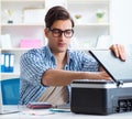 Young man employee working at copying machine in the office Royalty Free Stock Photo
