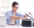 Young man employee working at copying machine in the office Royalty Free Stock Photo