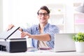 The young man employee working at copying machine in the office