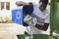 Young Man Emptying Household Recycling Into Green Bin Royalty Free Stock Photo