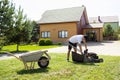 Young man emptying lawnmower grass catcher.