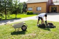 Young man emptying lawnmower grass catcher.