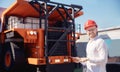 Young man engineer in helmet with tablet computer in hands on background of truck for coal mining ore Royalty Free Stock Photo