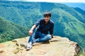 Young man enjoying the beauty of nature from a mountain cliff, 4500 feet above from the ground