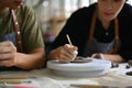 Young man enjoying creative process, decorating ceramic in art workshop