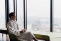 Young man enjoying evening coffee and beautiful sunset landscape of the city while standing by the window