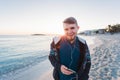 Young man enjoying the music on white sandy beach. Happy tourist relaxing on vacation. Royalty Free Stock Photo