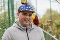 Young man enjoying at the zoo. Becoming friend with birds. Smiling and enjoying with animals