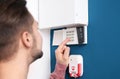 Young man entering code on security alarm system, indoors Royalty Free Stock Photo