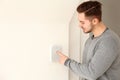 Young man entering code on security alarm system, indoors Royalty Free Stock Photo