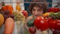 A young man examines a refrigerator filled with healthy products: vegetables, fruits, berries. Portrait of a satisfied Royalty Free Stock Photo