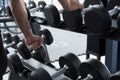 young man execute exercise in fitness center. male athlete choose dumbbell in gym. sporty guy working out in health club. Royalty Free Stock Photo