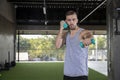 Young man exercise using dumbbells at fitness center.  Determined men  lifting weights  for workout in gym Royalty Free Stock Photo