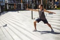 Young man exercising outside. Guy standing in yoga position alone at steps and stretching hands forward and backward