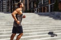 Young man exercising outside. Side view in motion of strong muscled guy running and training himself. Powerful running