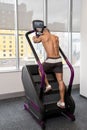 Young Man Exercising On A Stepper Back View