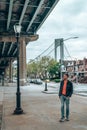 Young man exploring Brooklyn in New York under Verrazzano-Narrows bridge Royalty Free Stock Photo