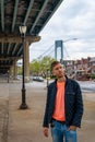 Young man exploring Brooklyn in New York under Verrazzano-Narrows bridge Royalty Free Stock Photo