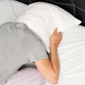 Young man face down in bed covering his head with a pillow Royalty Free Stock Photo