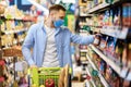 Young man in face mask with cart shopping in hypermarket Royalty Free Stock Photo