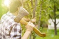 Young man in the farm garden working with axe and cutting the fruit treeon summer day a Royalty Free Stock Photo
