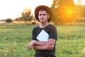 Young man farmer in cowboy hat at agricultural field on sunset holding tablet. Portrait of happy man on nature Royalty Free Stock Photo