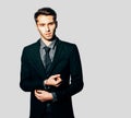 A young man in a fashionable suit posing on gray background. Indoor. Warm color. Royalty Free Stock Photo