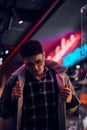 A young man fashionably dressed standing in the street at night. Illuminated signboards, neon, lights. Royalty Free Stock Photo