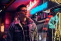 A young man fashionably dressed standing in the street at night. Illuminated signboards, neon, lights. Royalty Free Stock Photo